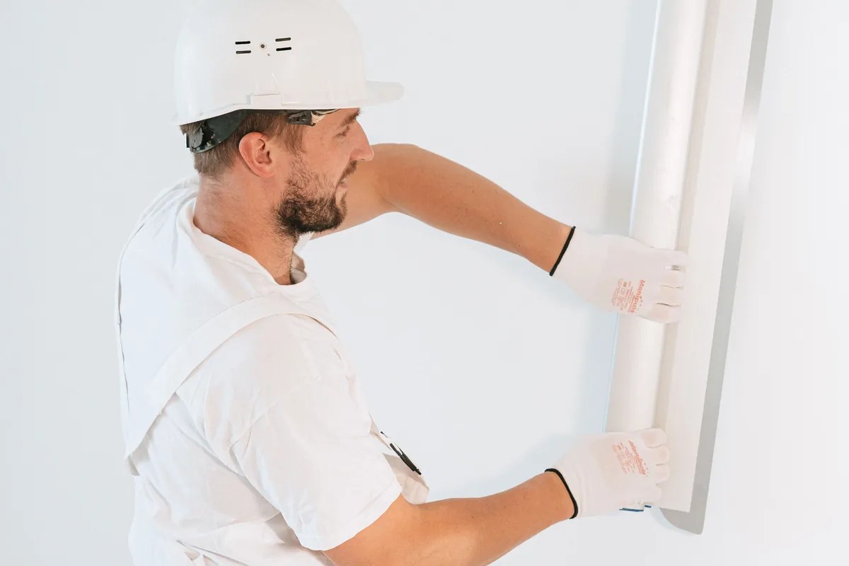 Contractor repairing drywall and installing a window