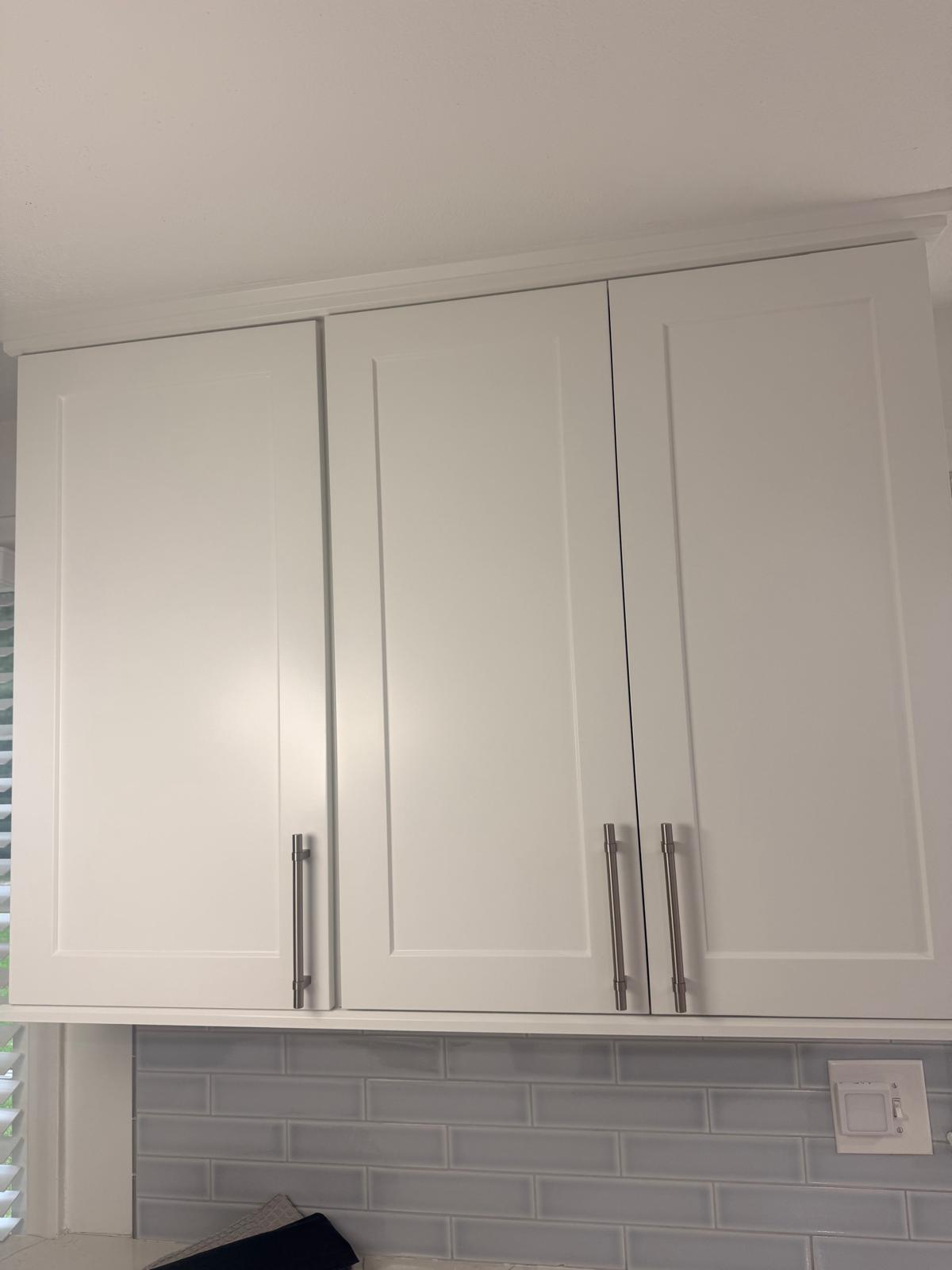 Close view of finished white kitchen cabinet doors and hardware